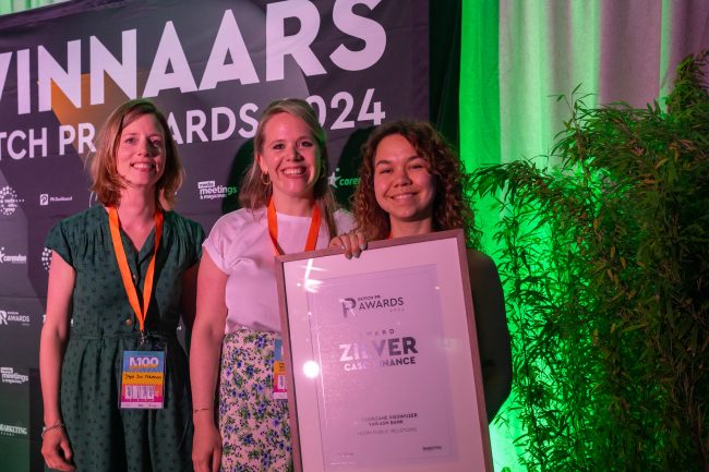 Joyce van HvdM en Floor en Shamal van ASN Bank houden een fotolijst met de Zilveren Dutch PR Award vast.