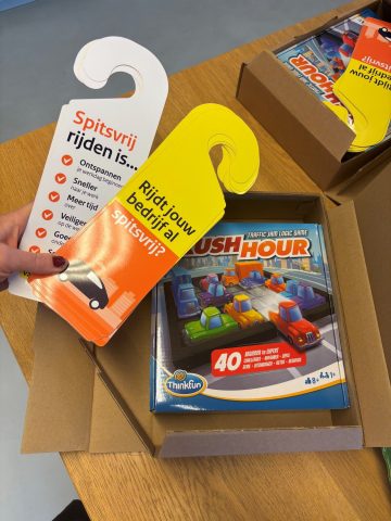 Deurhangers voor de campagne spitsvrij rijden. Op tafel ligt het spel rush hour.
