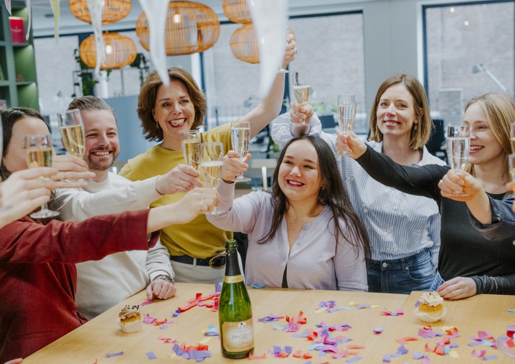 Van links naar rechts: Jill, Joeri, Daniëlle, Claire, Joyce en Lotte. Proosten naar elkaar toe in feestelijke setting.